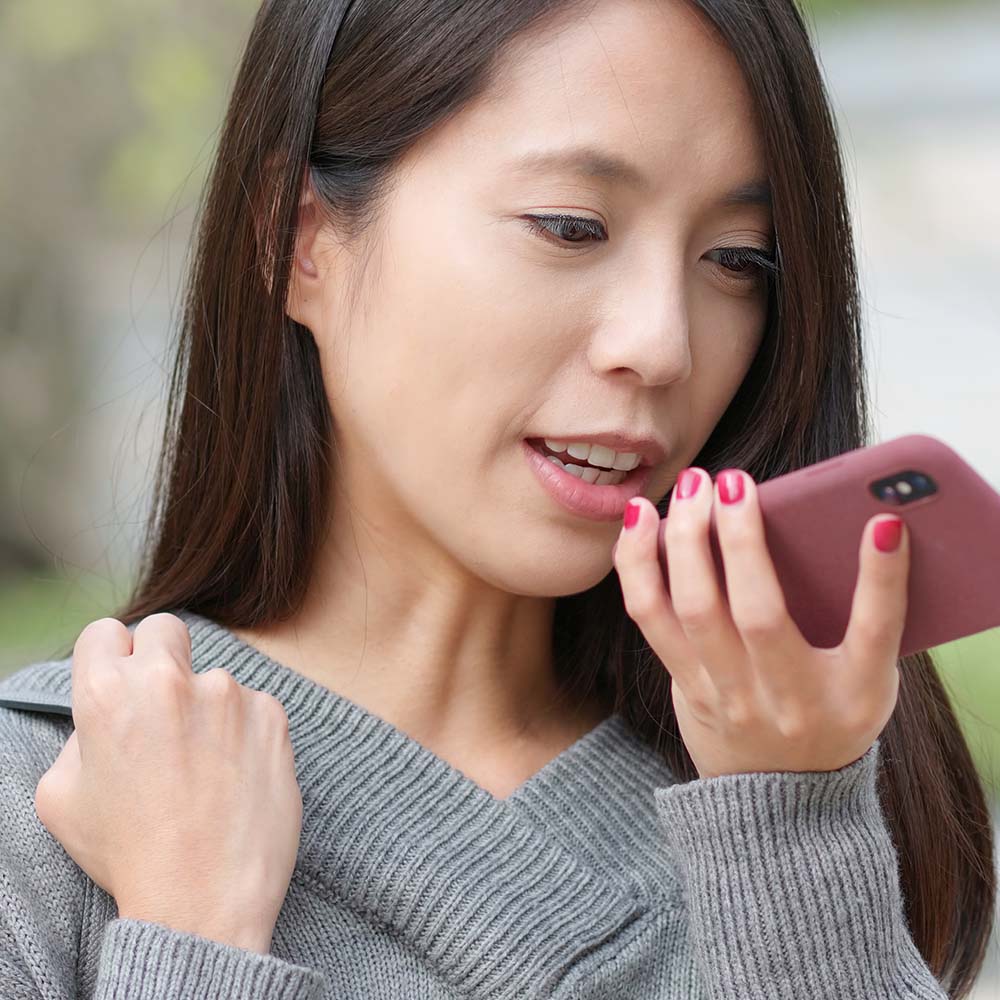 Young woman sending audio message on cellphone